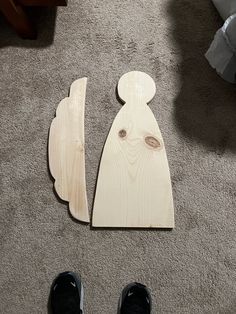 a pair of black shoes sitting on the floor next to a wooden angel cutout