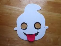 a white mask with a red tongue sticking out it's tongue is sitting on a wooden surface