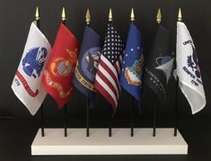 a bunch of flags that are sitting on a stand in front of a black wall