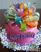 a birthday cake decorated with ribbons and flowers