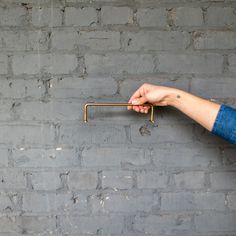 a person's hand holding onto a metal bar on a brick wall with grey paint