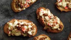 several pieces of bread with various toppings sitting on a baking sheet, ready to be eaten