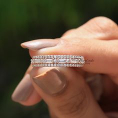 a woman's hand holding a wedding band with three rows of diamonds on it