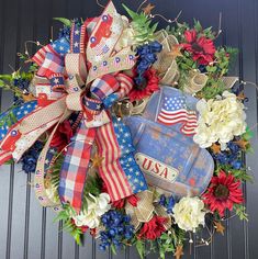 a patriotic wreath with an american flag, flowers and a suitcase on the front door