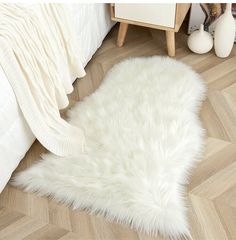 a white sheepskin rug is on the floor next to a bed and nightstands