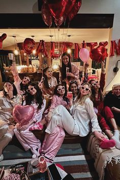 a group of women sitting on top of a couch in front of balloons and streamers