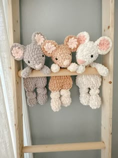 three stuffed animals are hanging on a ladder