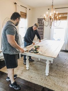 two men are working on a table in the living room