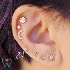 an ear with five different stars and moon designs on the inside of it, as well as two piercings