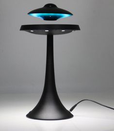 a black table lamp with a blue light on it's side and a cord attached to the base