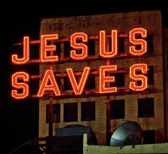 a large neon sign that says jesus saves on the side of a building at night