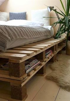 a bed made out of wooden pallets with a plant in the corner next to it