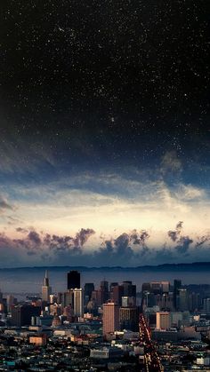 the city skyline is lit up at night with stars in the sky and some clouds