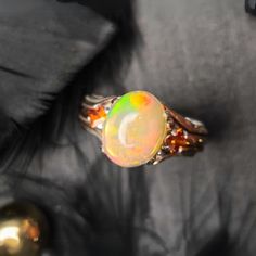 Unveil the magic of October with this stunning Fire Opal and Garnet Ring, a true masterpiece that captures the enchanting play of colors found in the finest opals. Set in a beautifully designed gold and silver band, this ring is a bold statement piece that's as unique as the person who wears it. The centerpiece of this ring is a mesmerizing fire opal, with its captivating flashes of orange, yellow, and green. Each time the light hits the opal, it reveals a new facet of its beauty, making it a pe Welo Opal Ring, Opal Ring Silver, Silver Garnet Ring, Sterling Silver Opal Ring, Gold Opal Ring, Handmade Gold Ring, Gold Leaf Rings, Blue Opal Ring, October Birthstone Rings