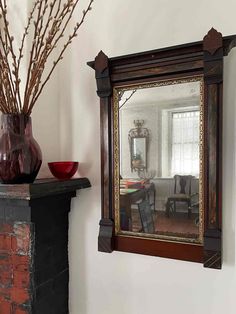 a mirror and vase sitting on top of a mantle