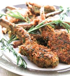 some food is sitting on a plate with rosemary sprigs and seasoning around it