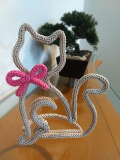 two crocheted hearts are sitting on a table next to a potted plant