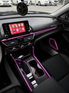 the interior of a car with pink trims and electronic devices in it's center console