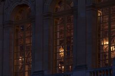 the windows are lit up at night in front of an old building with ornate architecture