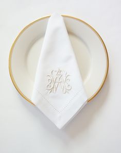 a white plate topped with a napkin and a gold rimmed dish cloth on top of it