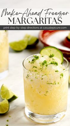 a close up of a margarita in a glass with limes on the rim and another drink behind it