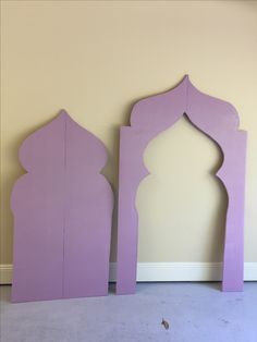 two purple wooden arches against a beige wall