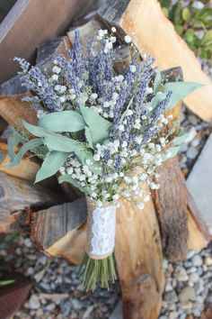 a bouquet of lavenders and baby's breath sits on a piece of wood