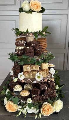 a three tiered cake is decorated with flowers and chocolates on the top layer