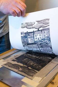 a person is printing pictures on a large sheet of white paper with black and white ink