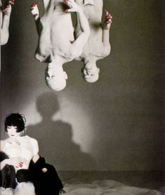 a black and white photo of a woman sitting on a bed with her legs up in the air