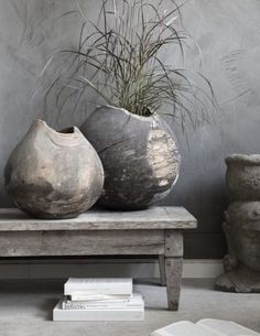 three large vases sitting on top of a wooden bench next to a planter