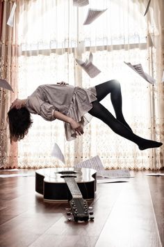 a man falling off his guitar in the air with papers flying all over him and around him