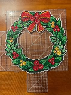 a cross stitch christmas ornament with a bow on it's front and side