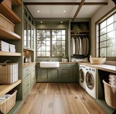 a washer and dryer in a room with green cabinets, wood flooring and open shelving