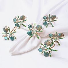 three brooches are sitting on top of a white cloth with pearls and green leaves