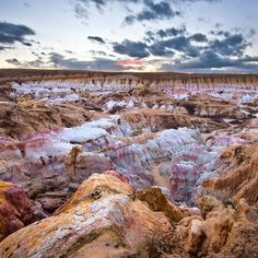 the sun is setting over an area with many colorful rocks and dirts in the foreground