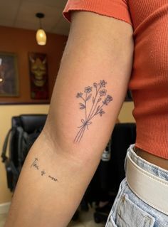 a woman's arm with a small flower tattoo on it