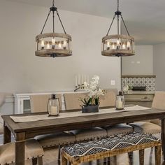 two chandeliers hanging over a dining room table with chairs and bench in front of it