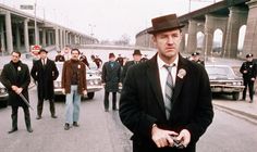 a man in a suit and tie walking down the street with other men behind him