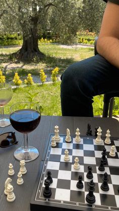 a man sitting at a table next to a chess board and wine glass on the table