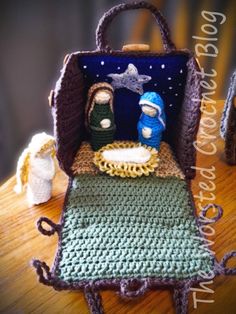 a crocheted nativity scene is displayed on a wooden table with other items