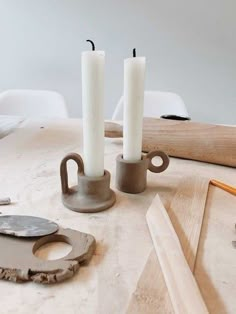 two candles are sitting on a table next to some scissors and other woodworking tools