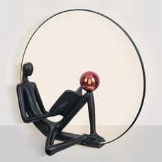 a black figure sitting in front of a red ball