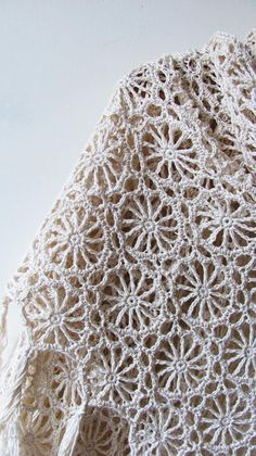 a white crocheted shawl is on display