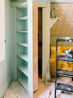 an empty room with a ladder in the corner and shelves on the wall behind it