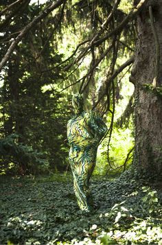 a woman is walking through the woods with her back turned to the camera and arms behind her head