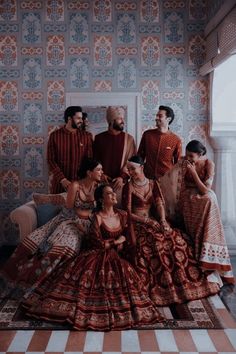 a group of people standing next to each other in front of a wallpapered room