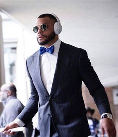 a man in a suit and bow tie with headphones on walking through an airport