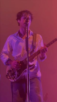 a man playing guitar while singing into a microphone