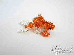 an orange and white beaded brooch sitting on top of a white table next to a pair of scissors